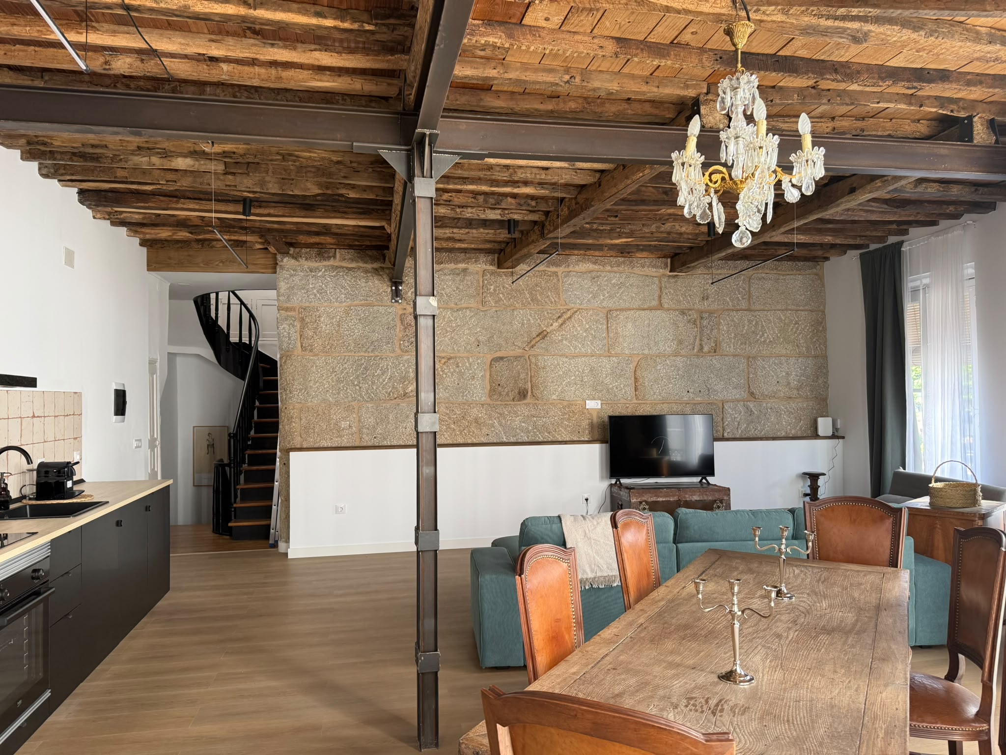 Salón-comedor de Casa Millo Primero con muro de piedra y vista a la escalera